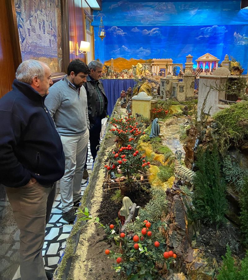 Hombres de la parroquia ante el belén que montan cada Navidad.