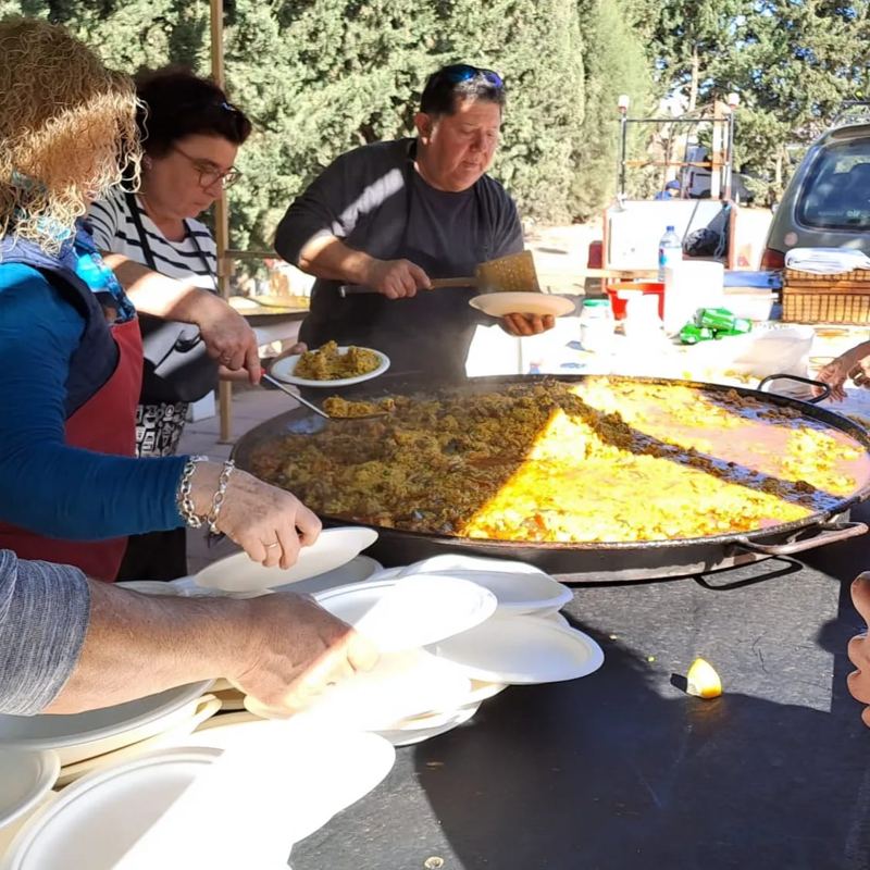 Voluntarios sirviendo paella en una comida de la parroquia al aire libre.